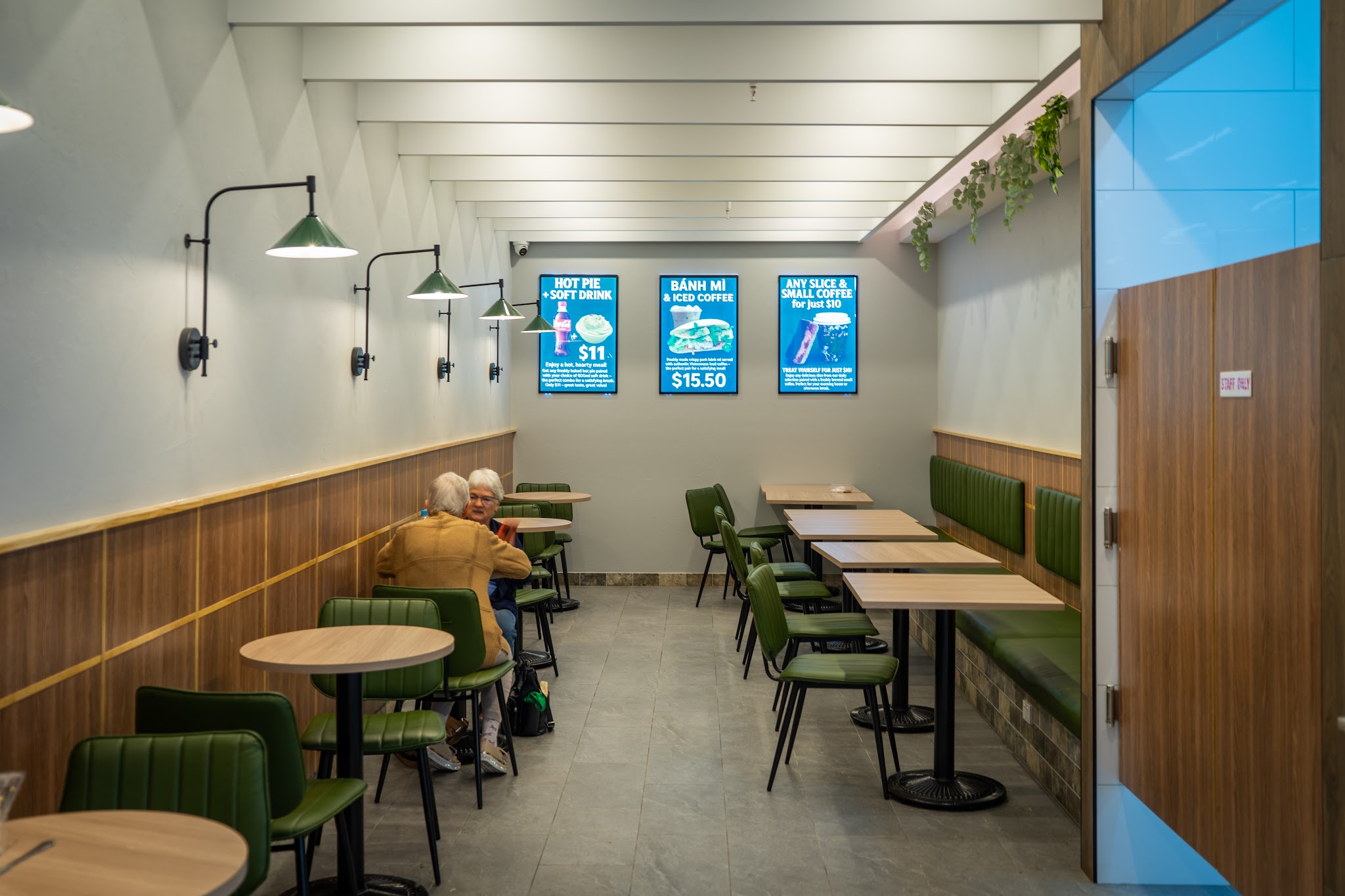 Seating area with green booth seats, timber panelling and pendant lamps