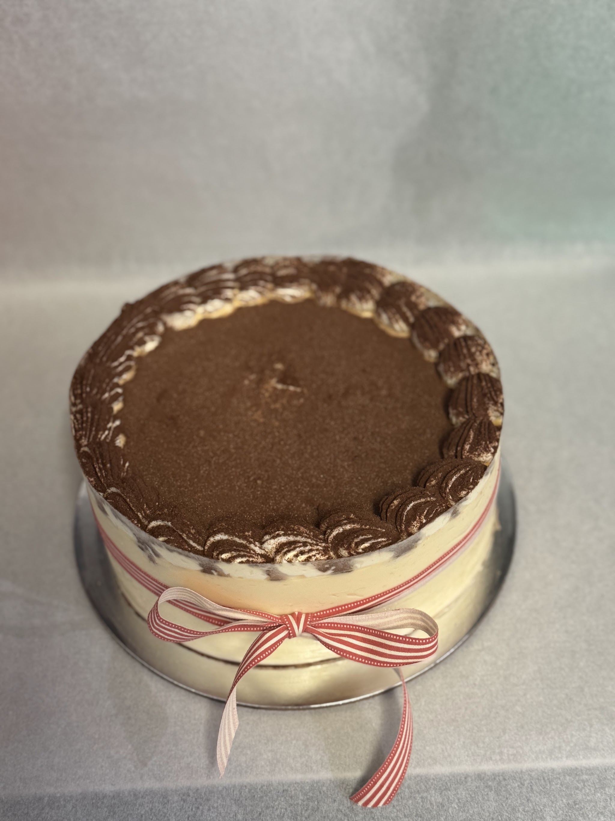 Tiramisu cake dusted with cocoa and tied with a striped ribbon